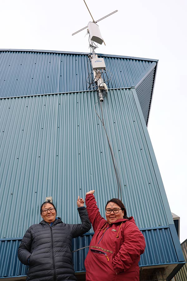 Two women pointing at an antenna on the side of a building
