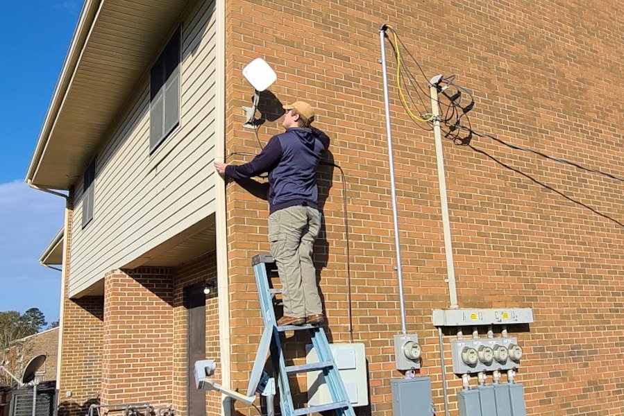 a man standing on a ladder installing Internet hardware