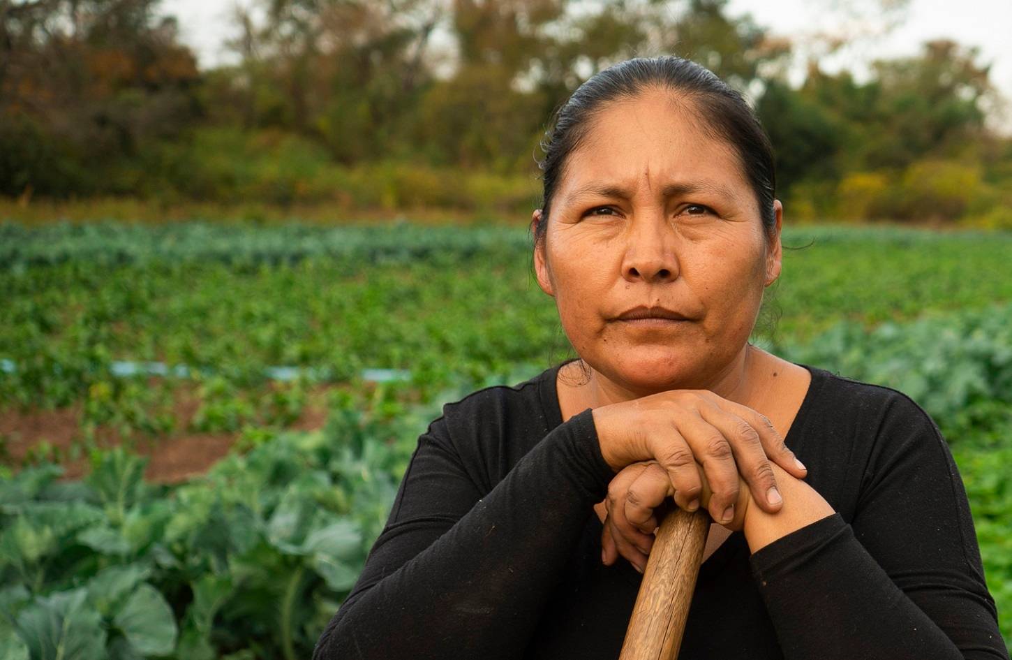 A woman in a garden holding a garden tool