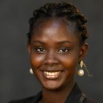 A young woman wearing a black blazer and earrings.