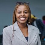 A professional woman wearing a suit and glasses with a pleasant smile on her face