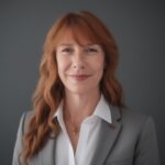 A professional woman with fiery red hair wearing a formal business suit.