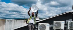Man on a roof holding a satellite dish for a community network