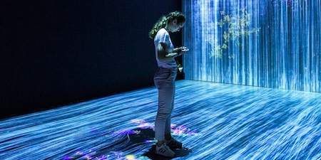 A woman standing in front of a large screen projected with water.