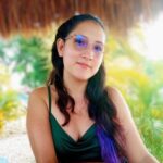 a woman with sunglasses and long hair sitting at table outdoors