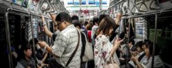 A photo of a busy subway car with multiple people looking at their phones.