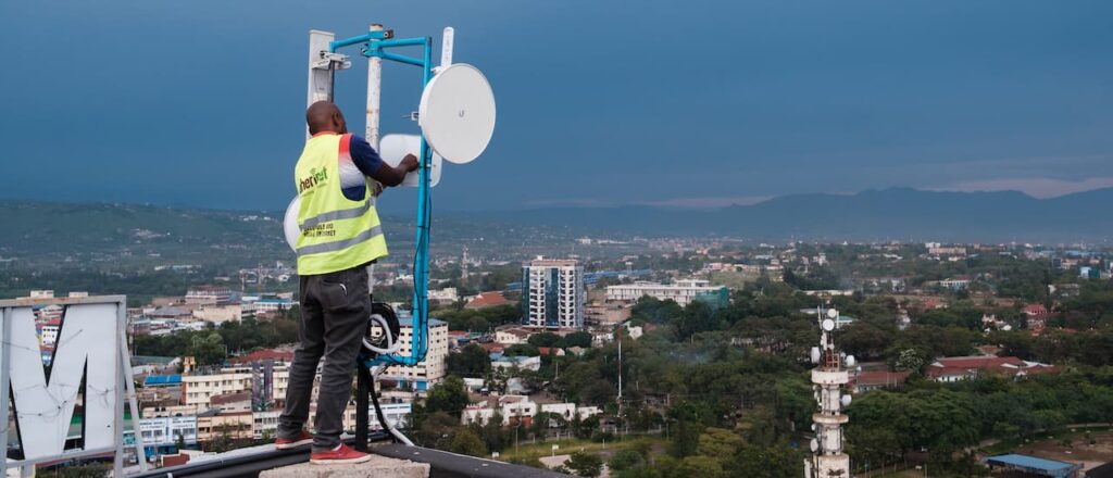 A man in Kenya stands on the roof of a building where a community network point of presence is located.
