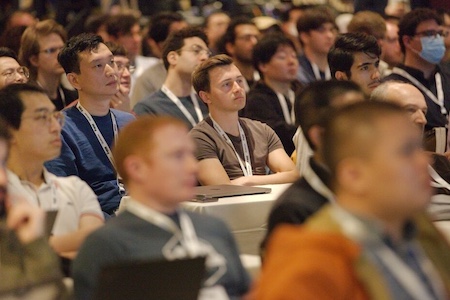 people seated in a meeting room, participating in a conference.