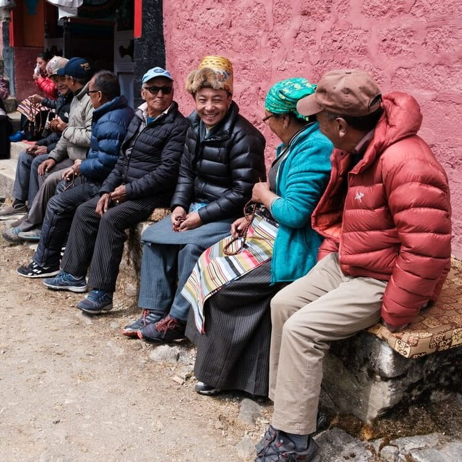 A diverse group of individuals seated on a bench outdoors