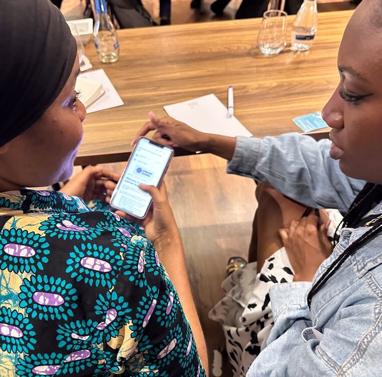 Two women at a table, focused on their phones