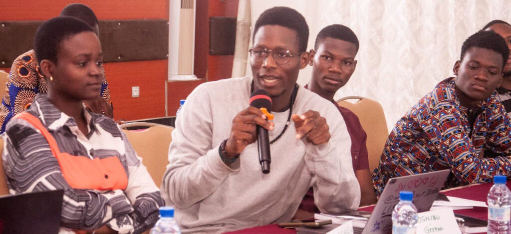 A man speaks into a microphone at a Benin Chapter Universal Acceptance event