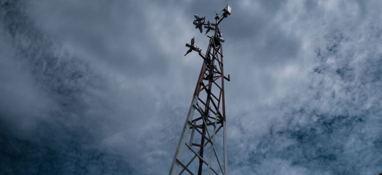 A network tower and equipment in front of a cloudy sky
