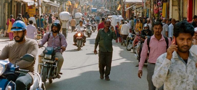 People walk and ride down a street in India