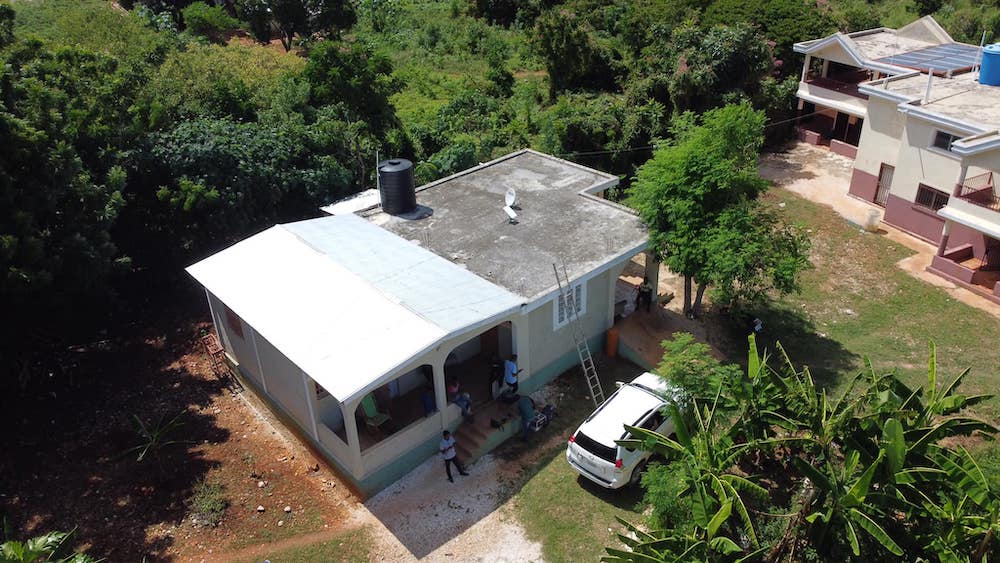 A white van and a couple people outside a building in Haiti