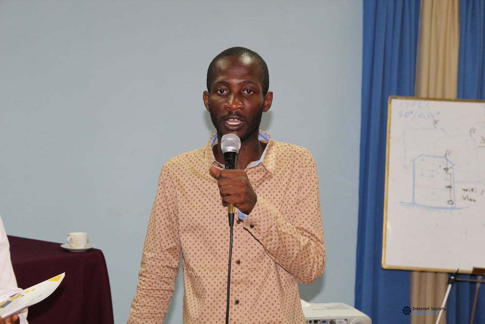 A man stands and speaks into a microphone