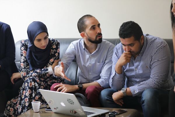 Several individuals focused on a laptop, sharing ideas
