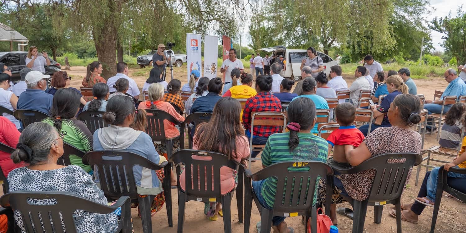 Several individuals sitting in chairs outside, participating in an event.