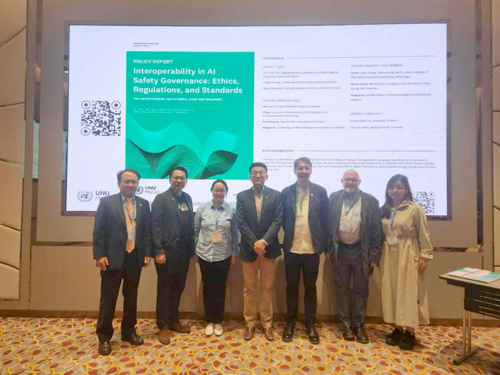 Seven people stand in front of a screen at a UK Chapter presentation