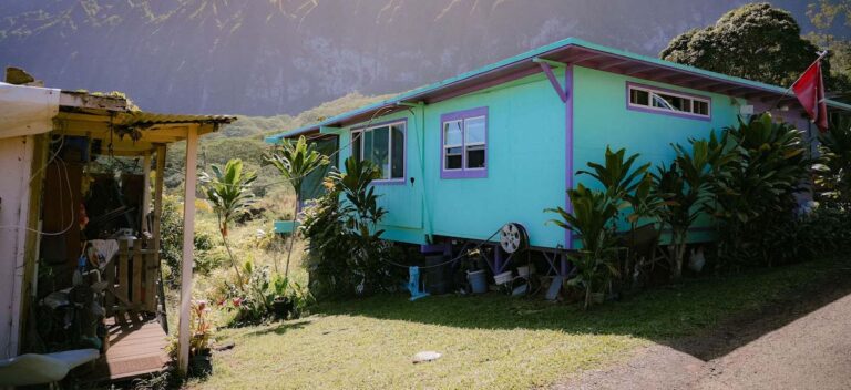 A small, blue house. In the background, there are mountains.