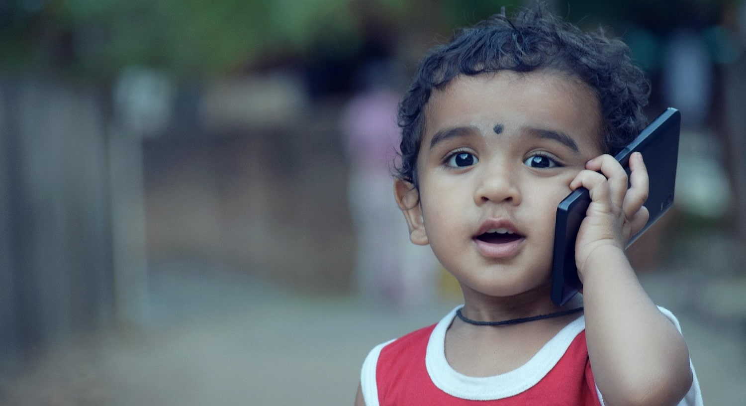 A young child is animatedly talking on a cell phone