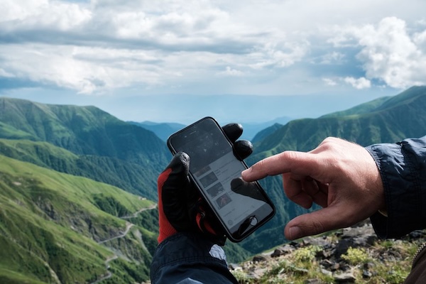 A person in the mountains holds a cell phone