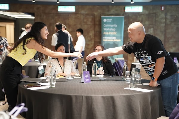A man and a woman shake hands across a table, symbolizing agreement
