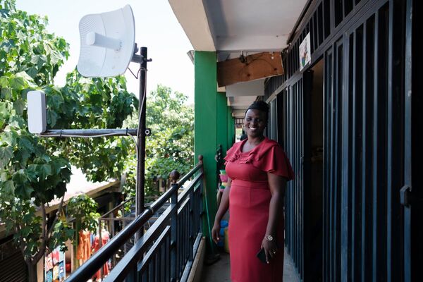 A woman wearing a red dress poses on a balcony