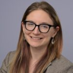 a headshot of a woman wearing glasses smiling
