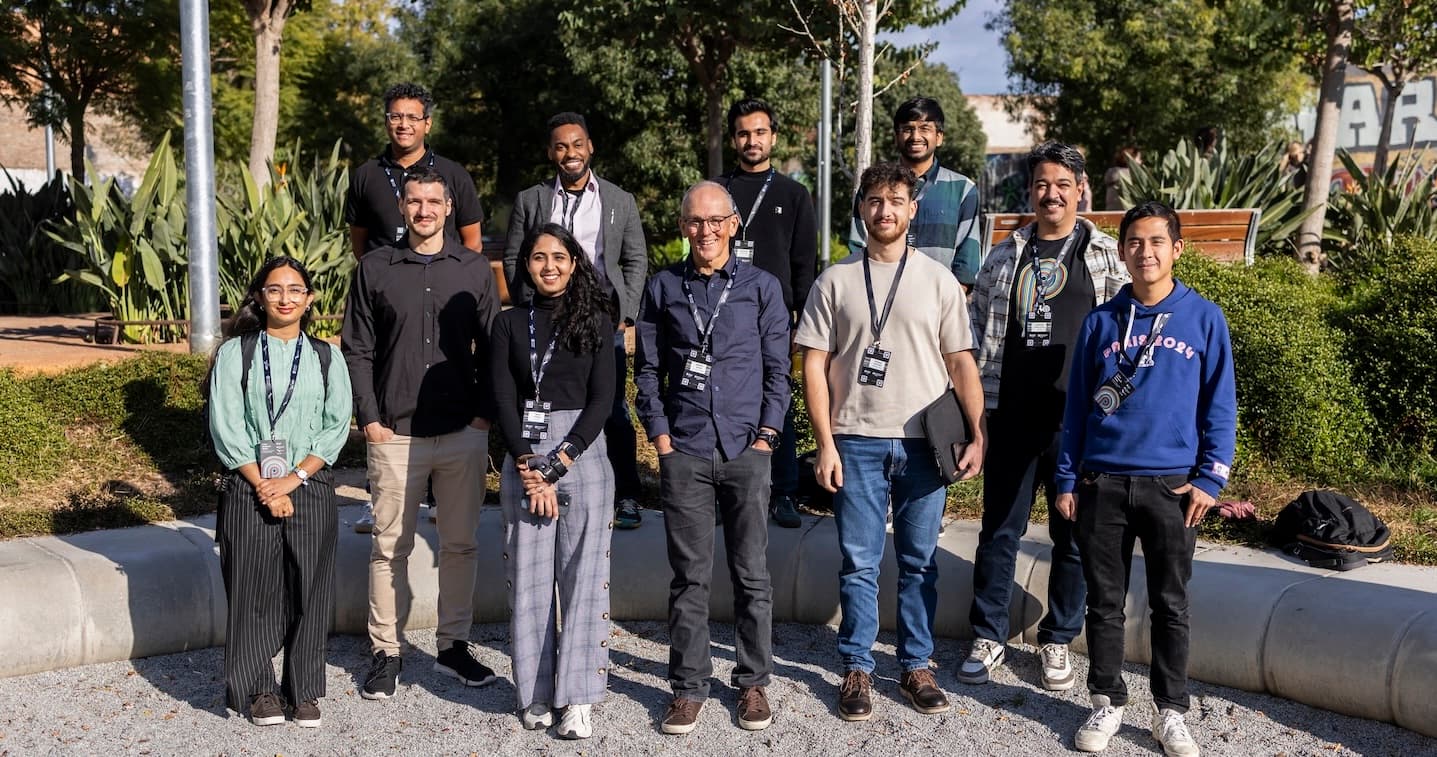 Several individuals gather in front of a building, posing together