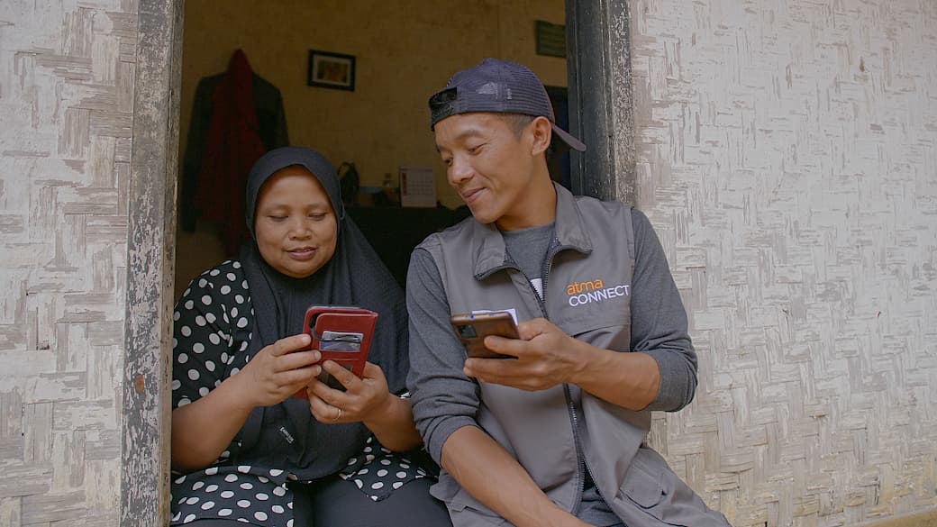 a man and a woman looking at their smartphone screens smiling