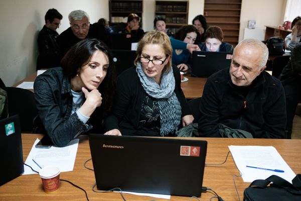 a group of people in the classroom looking at laptop screen