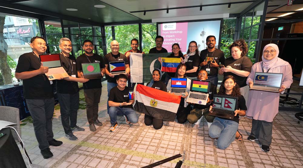 A group of people at a community workshop pose with images of their flags