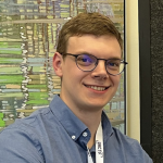 A man with a grey shirt with a ribbon around his neck