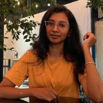 A woman with glasses in a yellow shirt