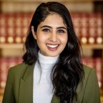 A woman in white turtle neck and olive green blazer jacket