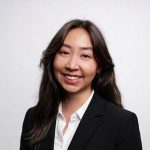 A woman in a black suit ad white shirt smiling.