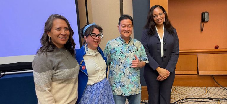 Four people stand together at a workshop