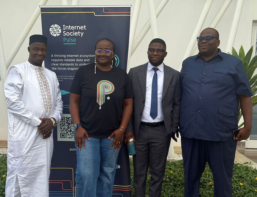 Four people stand next to an Internet Society Pulse sign at an Internet Measurement Fourm