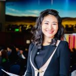 A woman in a business suit smiles confidently at the camera