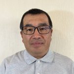 A man with glasses wearing a grey shirt
