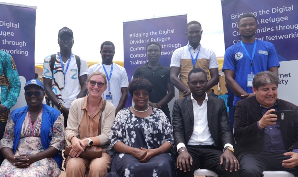 A group of people sit and stand together at a refugee connectivity event