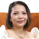 A woman in a white dress sits gracefully on an orange couch