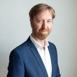 A bearded man wearing a suit jacket