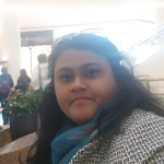 A woman in black and white jacket with blue scarf