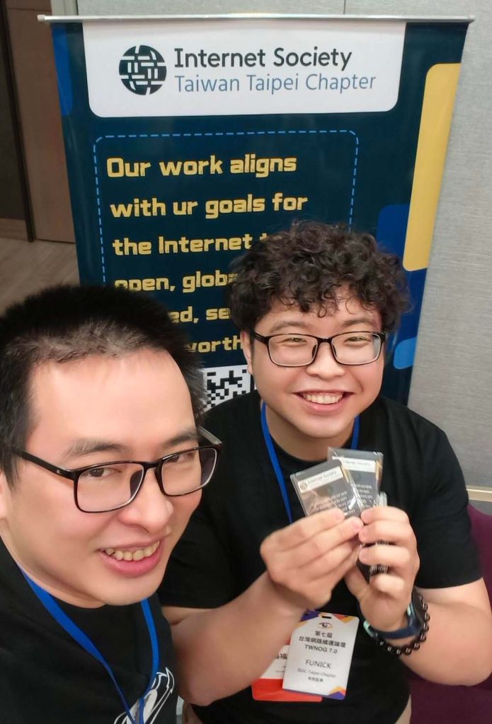 Two peopel smile together in front of an Internet Society Taiwan Taipei sign.