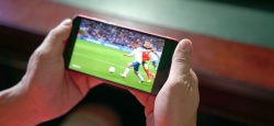 Two hands hold a phone playing a soccer match.