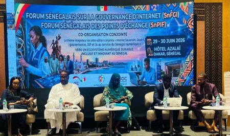 Five people sit in chairs in front of a screen at an event in Senegal