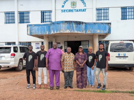 Seven people stand together outside a Njala University building