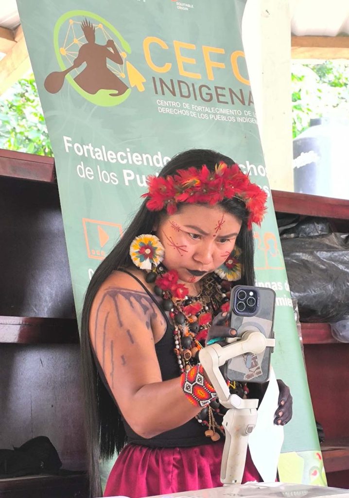An Indigenous woman looks at a phone in her hand.