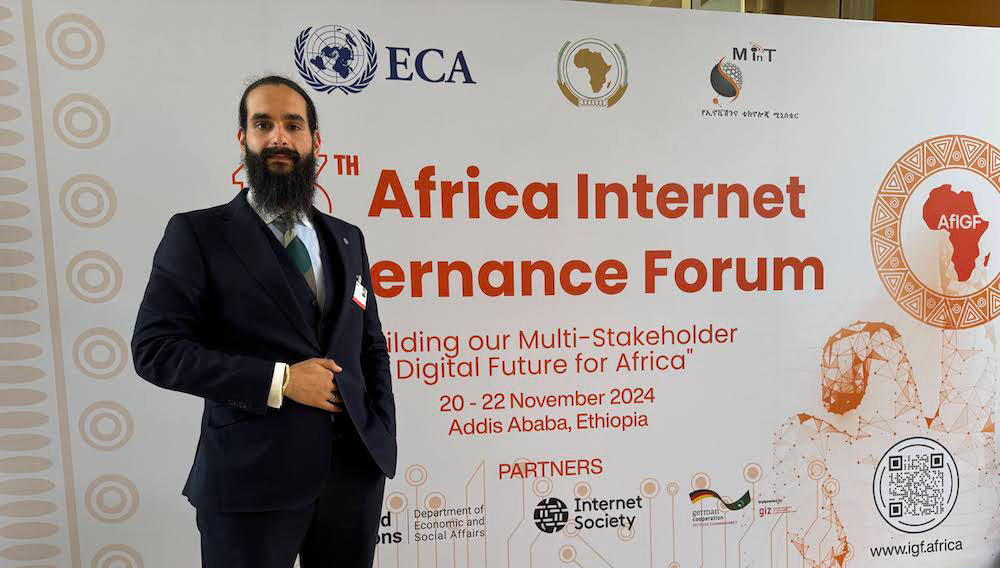 Amged B. Shwehdy stands in front of an Africa Internet Governance Forum sign.